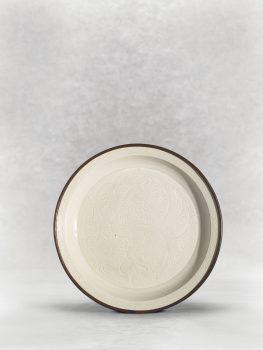A Ding “peony” dish, from the Northern Song–Jin Dynasty (960–1234), showcases the modest elegance of Song ceramics. Two tasteful peony blossoms are carved into the center, giving the otherwise unembellished dish a whimsical touch. (Christie’s)