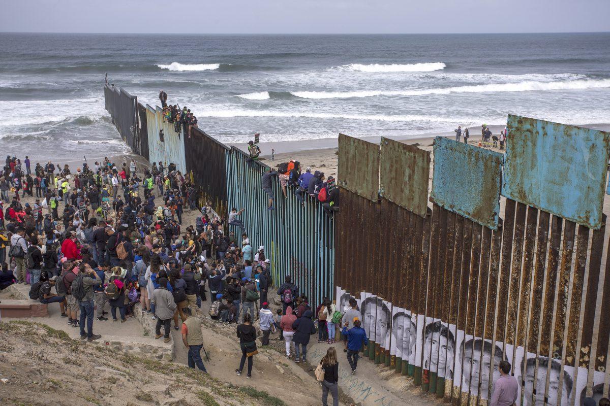 People climb a section of border fence to look into the United States as a caravan of Central American asylum-seekers arrive at the border in Tijuana, Mexico, on April 29. (David McNew/Getty Images)