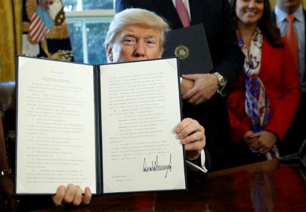 FILE PHOTO - After signing, U.S. President Donald Trump holds up an executive order rolling back regulations from the 2010 Dodd-Frank law on Wall Street reform at the White House in Washington Feb. 3, 2017. (REUTERS/Kevin Lamarque)