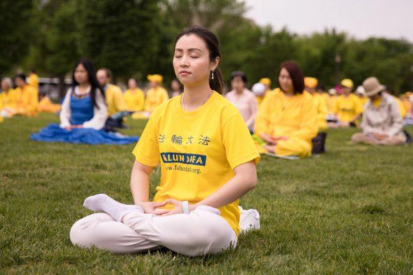 Linh Pham meditates during a Falun Dafa Day celebration on the National Mall in Washington on May 5, 2018. (Samira Bouaou/The Epoch Times)