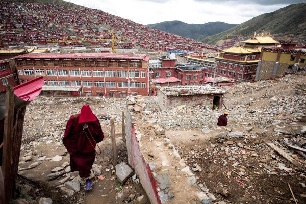 A nun walking amid the debris of demolished houses at the world's most important institution for Tibetan Buddhist learning, the Larung Gar monastery, in Sertar County in southwest China's Sichuan Province, on May 29, 2017. The Chinese regime has ordered the demolition since 2016. (Johannes Eisele/AFP/Getty Images)