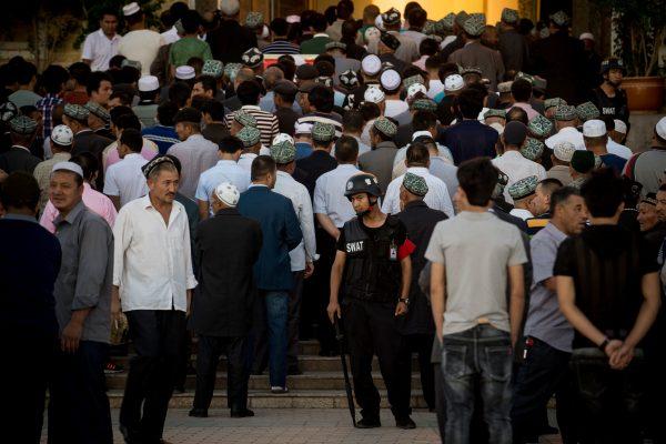 A policeman standing guard as Muslims arrive for the Eid al-Fitr morning prayer at the Id Kah Mosque in Kashgar, Xinjiang, on June 26, 2017. (Johannes Eisele/AFP/Getty Images)