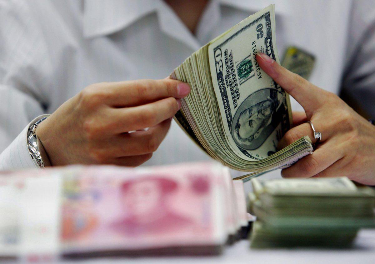 A bank teller counts the stack of Chinese yuan and U.S. dollars at a bank in Shanghai, China, on July 22, 2005. (STR/AFP/Getty Images)