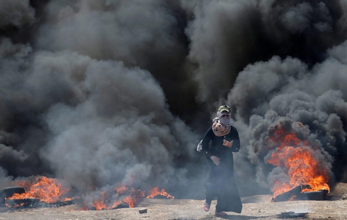 A female Palestinian demonstrator gestures during a protest against U.S. embassy move to Jerusalem and ahead of the 70th anniversary of Nakba, at the Israel-Gaza border, east of Gaza City May 14, 2018. REUTERS/Mohammed Salem