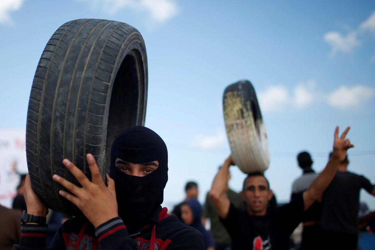 Palestinian demonstrators carry tires during a protest against U.S. embassy move to Jerusalem and ahead of the 70th anniversary of Nakba, at the Israel-Gaza border, east of Gaza City May 14, 2018. REUTERS/Mohammed Salem