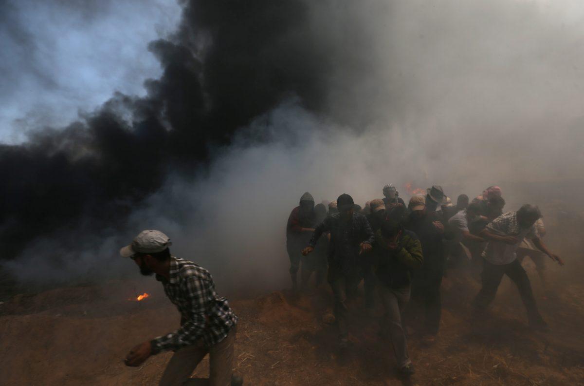 Palestinian demonstrators run for cover during a protest against U.S. embassy move to Jerusalem and ahead of the 70th anniversary of Nakba, at the Israel-Gaza border in the southern Gaza Strip May 14, 2018. REUTERS/Ibraheem Abu Mustafa
