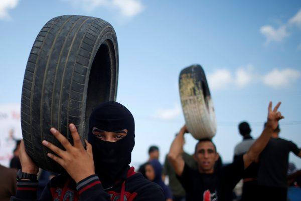 Palestinian demonstrators carry tires during a protest against U.S. embassy move to Jerusalem at the Israel-Gaza border, east of Gaza City May 14, 2018. (Reuters/Mohammed Salem)