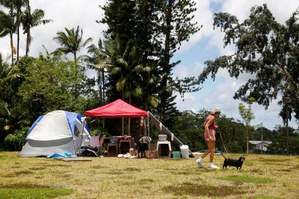 Pauline McLaren, 77, of Kapoho, walks one of her five dogs near her tents at a Red Cross evacuation center in Pahoa during ongoing eruptions of the Kilauea Volcano in Hawaii, U.S., May 15, 2018. (Reuters/Terray Sylvester)