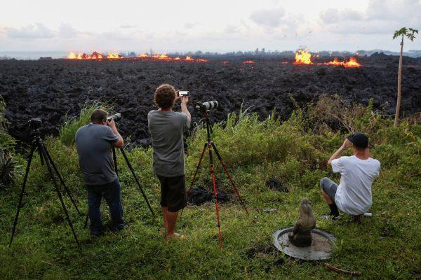 Photographers take photos of a fissure on the outskirts of Pahoa May 14, 2018. (REUTERS/Terray Sylvester)