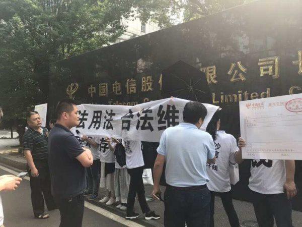 Victims holding up signs outside of Changsha branch of China Telecom. (Ms. Li)