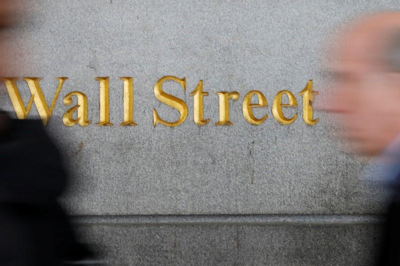 People walk by a Wall Street sign close to the New York Stock Exchange (NYSE) in New York on April 2, 2018. (Shannon Stapleton/Reuters)