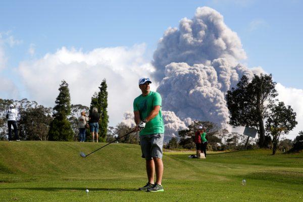 Sean Bezecny, 46, of Houston, Texas, takes a golf swing as ash erupts from the Halemaumau Crater near of the Kilauea Volcano in Hawaii, May 19. (Reuters/Terray Sylvester)