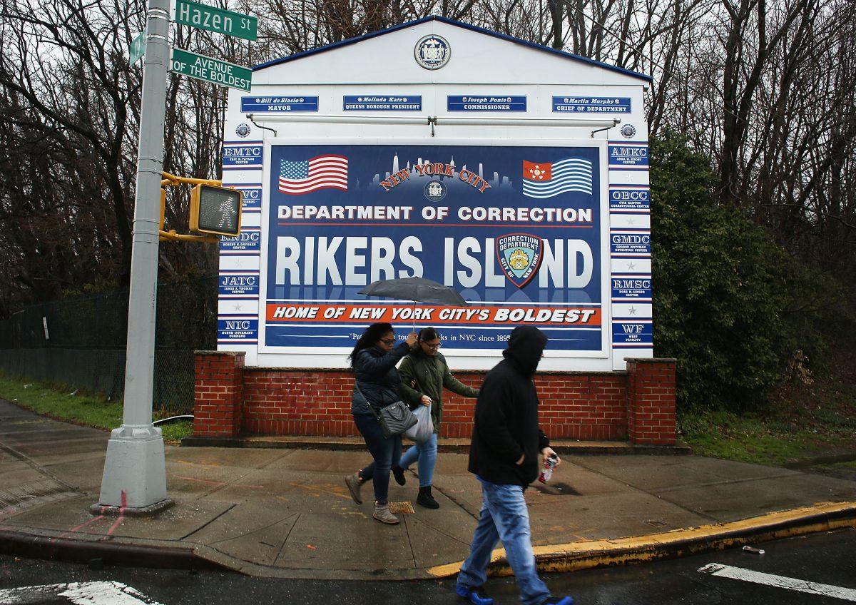 People walk by a sign at the entrance to Rikers Island in New York on March 31, 2017. (Spencer Platt/Getty Images)