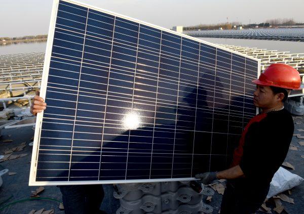 Chinese employees carrying a solar panel at a floating solar power plant in Huainan City, in China's eastern Anhui Province on Dec. 11, 2017. (AFP/Getty Images)