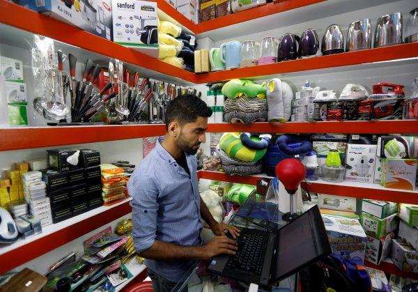 An Afghan shopkeeper works on his laptop at his online shop in Kabul, Afghanistan June 4, 2018. Picture taken June 4, 2018. (Reuters/Omar Sobhani)