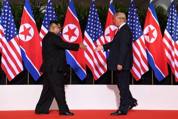 President Donald Trump and North Korea leader Kim Jong Un reach out to shake hands at the start of their historic summit, in Singapore on June 12, 2018. (SAUL LOEB/AFP/Getty Images)