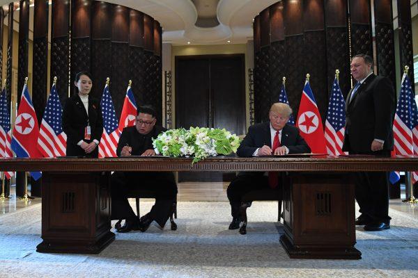 President Donald Trump and North Korea's Kim Jong Un sign a joint statement as Secretary of State Mike Pompeo (R) and Kim's sister, Kim Yo Jong, look on during the summit in Singapore on June 12, 2018. (SAUL LOEB/AFP/Getty Images)