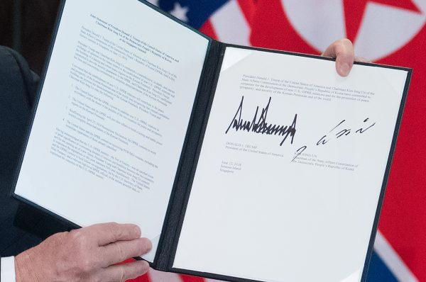President Donald Trump holds up a <a href="https://www.theepochtimes.com/full-text-of-trump-and-kims-joint-statement_2558906.html">document signed</a> by him and North Korea leader Kim Jong Un following a signing ceremony during their historic US-North Korea summit in Singapore on June 12, 2018. (SAUL LOEB/AFP/Getty Images)