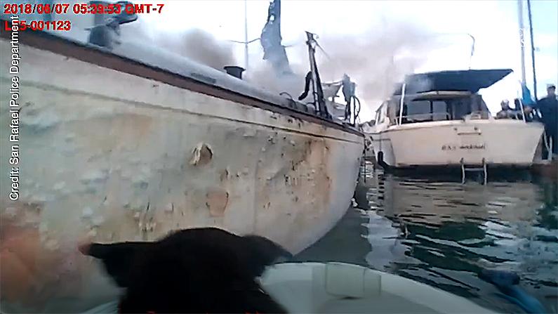 The head of the rescued dog pokes above the gunwales as the officer pushes off from the burning boat. (Screenshot via San Rafael Police Department)