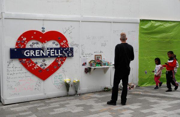 A man reads messages of condolence written on a hoarding at the base of Grenfell tower one year after the fire in Britain, in London, June 13, 2018. (Reuters/Peter Nicholls)