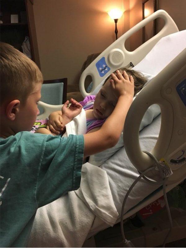 Addy's brother, Jackson, comforts her as she lies in a hospital bed. (Courtesy of Matt Sooter)