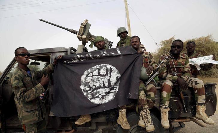 Nigerian soldiers hold up a Boko Haram flag that they had seized in the recently retaken town of Damasak, Nigeria, on March 18, 2015. (Emmanuel Braun/Reuters)