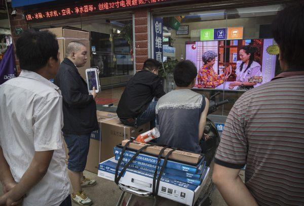 Men watch a program on a large television set in the window of an electronics shop in Wuhan City, Hubei Province on May 15, 2017. (Kevin Frayer/Getty Images)