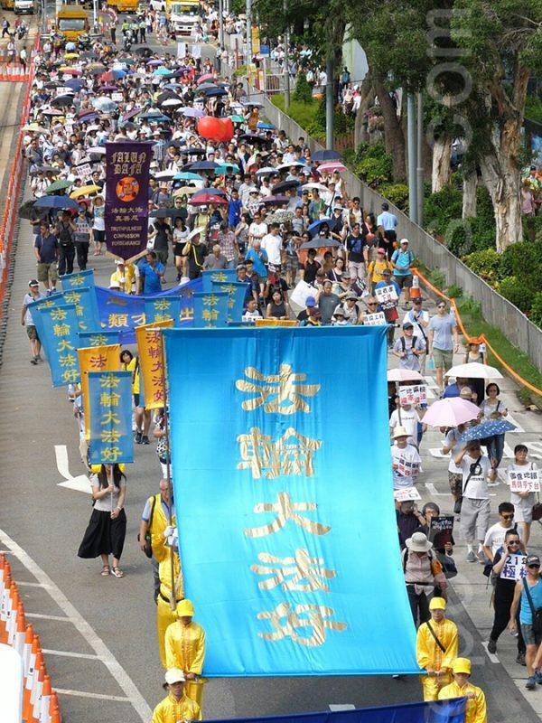 Falun Gong adherents hold up a giant blue banner with the words "Falun Dafa Is Good" in a parade in Hong Kong on July 1, 2018. (The Epoch Times)
