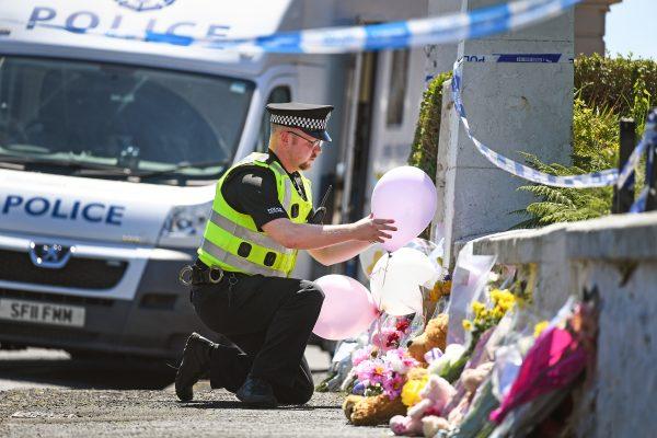A policeman leaves balloons for a member of the public at a house on the Isle of Bute following the conformation that six year old schoolgirl Alesha MacPhail was murdered on July 4, 2018 in Rothesay, Isle of Bute, Scotland. (Jeff J Mitchell/Getty Images)