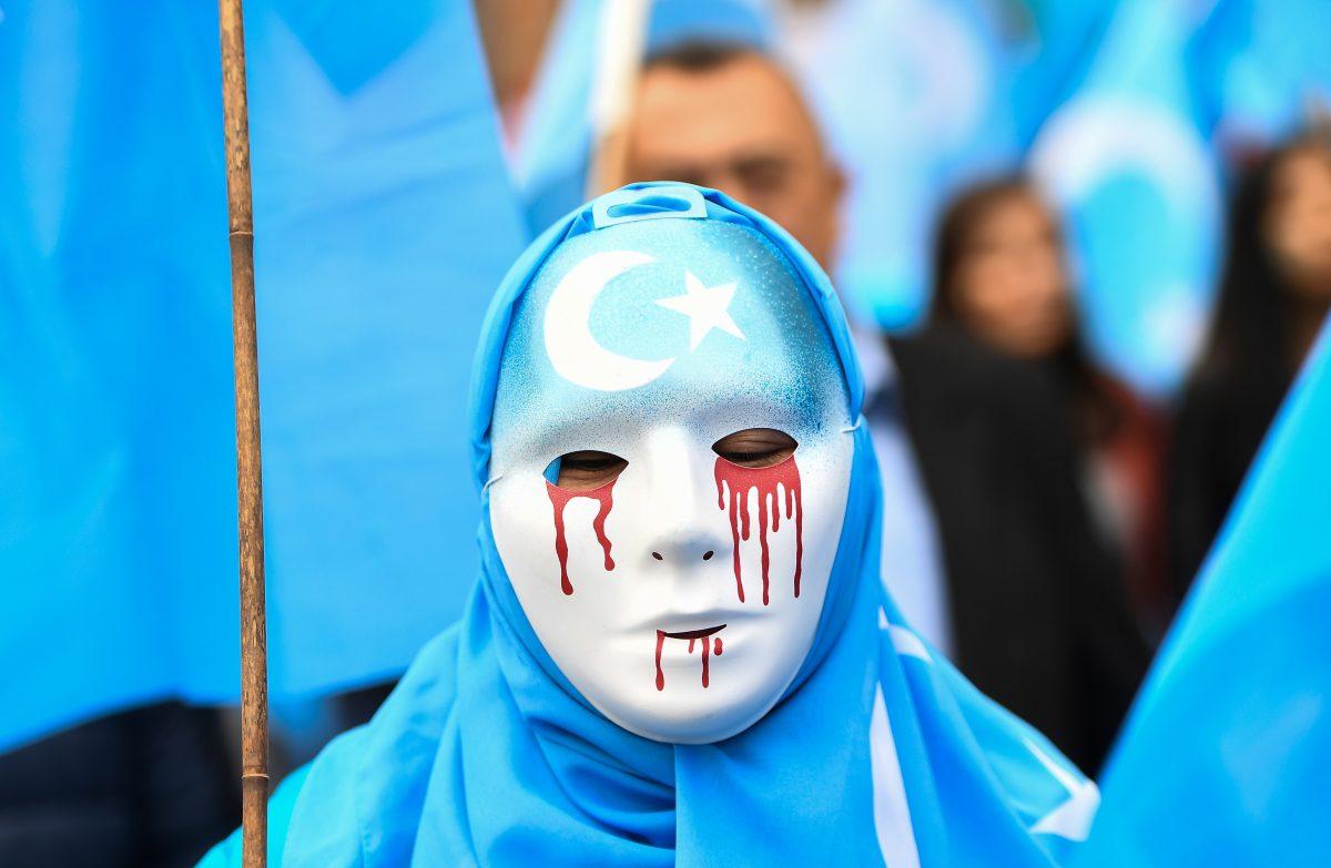 A person wearing a white mask with tears of blood takes part in a protest march of ethnic Uyghurs asking for the European Union to call upon China to respect human rights in the Chinese Xinjiang region and ask for the closure of "re-education center" where Uighurs are detained, during a demonstration around the EU institutions in Brussels on April 27, 2018. (EMMANUEL DUNAND/AFP/Getty Images)