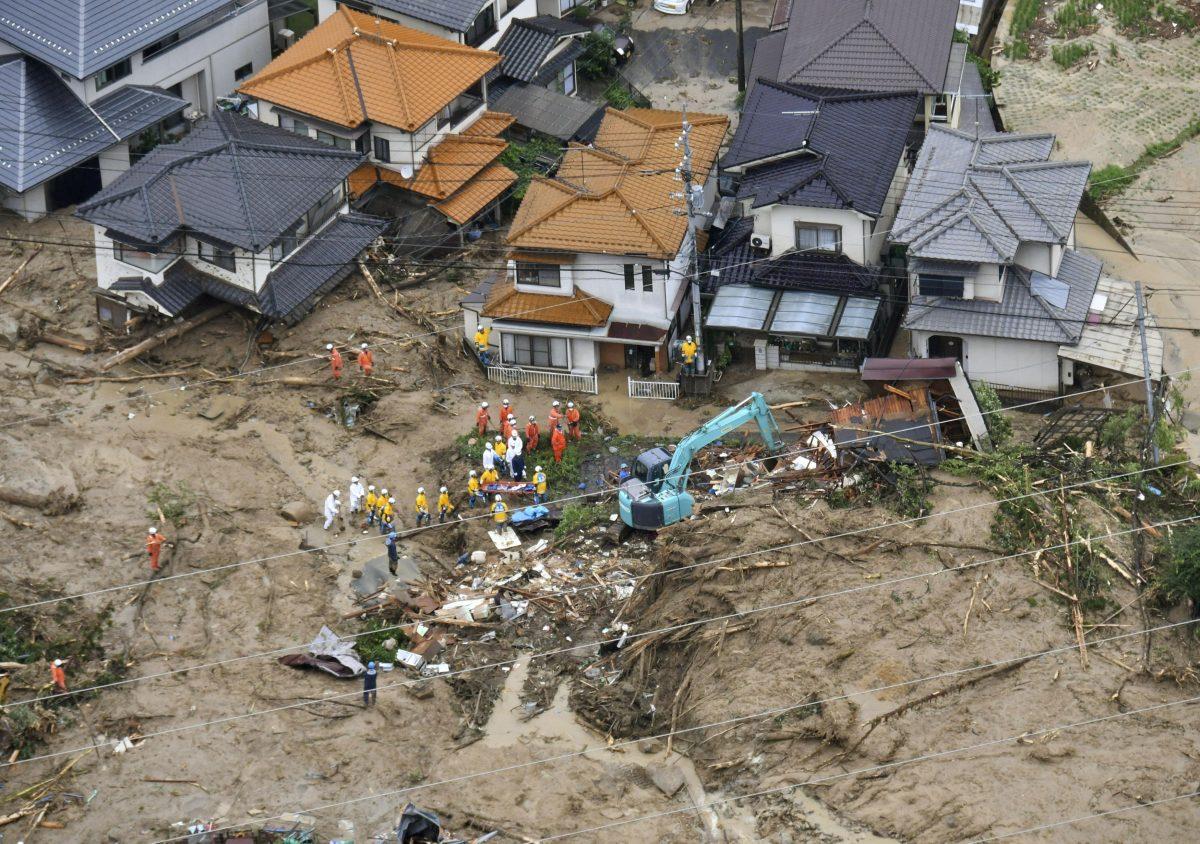 Rescue workers are seen next to houses damaged by a landslide following heavy rain in Hiroshima, western Japan, in this photo taken by Kyodo July 7, 2018. (Kyodo/Reuters)