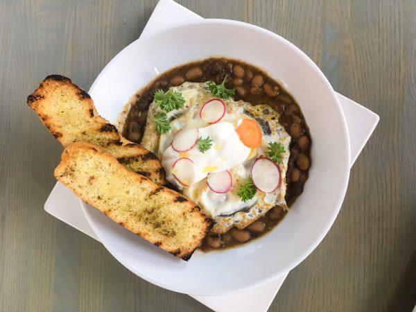 Pork and beef cassoulet with fried eggs, sour cream, and pesto bread from Nicks on Broadway. (Crystal Shi/The Epoch Times)