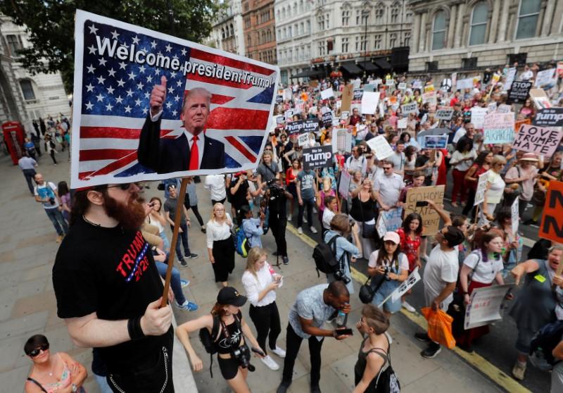 A man holds a poster welcoming U.S. President Donald Trump as demonstrators protest against his visit in central London, Britain, July 13, 2018. (Reuters/Yves Herman)