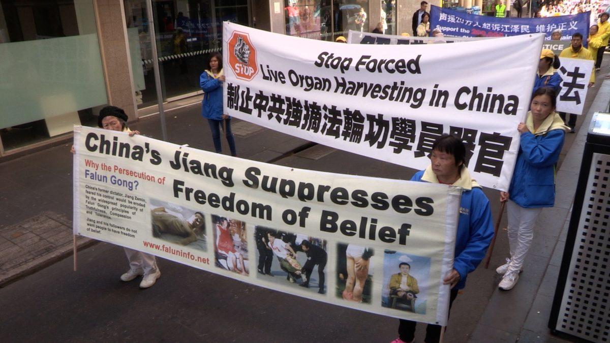 Falun Dafa practitioners holding banners raising awareness about forced organ harvesting and bringing Jiang Zemin to justice, in Melbourne, Australia on July 14, 2018. (Daniel Cameron/NTD)