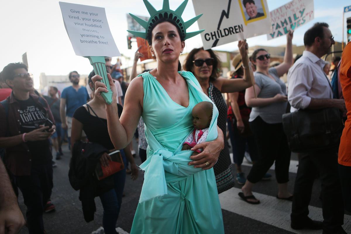 A protestor dressed as Lady Liberty carries a doll, depicting a baby of color, as demonstrators march at the 'Families Belong Together March,' culminating at a center where ICE detainees are held. (Mario Tama/Getty Images)