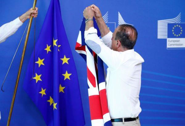 An official carries a Union Jack flag next to the European Union flag, ahead of a meeting between Dominic Raab and the EU's chief Brexit negotiator, Michel Barnier, in Brussels, July 19, 2018. (Reuters/Francois Lenoir)