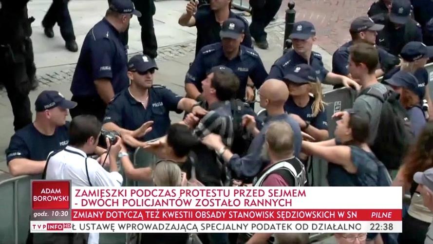 A protester identified in local media as Dawid Winiarski (weaking a checkered shirt) can be seen engaged in an apparent scuffle with the police before being arrested on Friday, July 20, outside the Polish Parliament in Warsaw. (Screengrab via TVP)