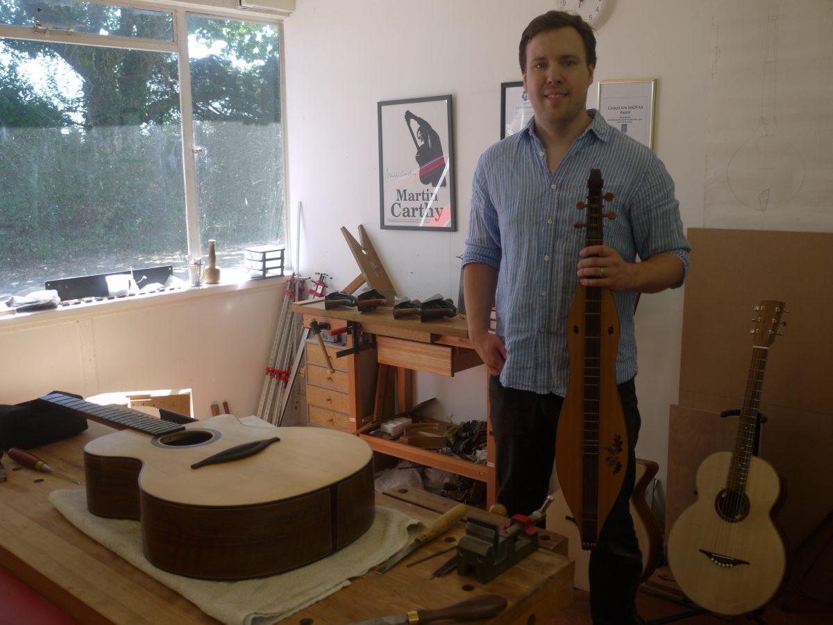 Holding a mountain dulcimer, Alex Potter makes his instruments entirely by hand, from start to hand-planed finish. (Courtesy of Alex Potter)