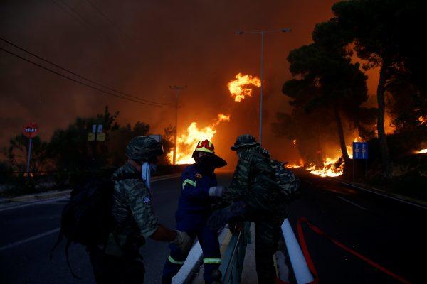 Firefighters and soldiers fall back as a wildfire burns in the town of Rafina, near Athens, Greece, July 23, 2018. (Reuters/Costas Baltas)