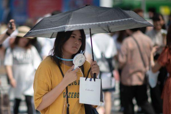 A woman uses a portable fan to cool herself in Tokyo on July 24, 2018, as Japan suffers from a heatwave. (Martin Bureau/AFP/Getty Images)