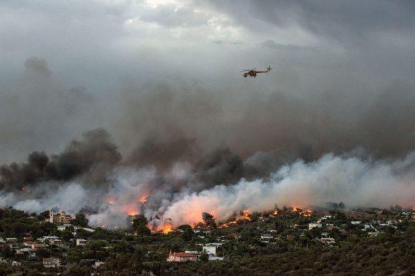 A firefighting helicopter flies over a wildfire raging in the town of Rafina near Athens, on July 23, 2018. (Angelos Tzortzinis/AFP/Getty Images)