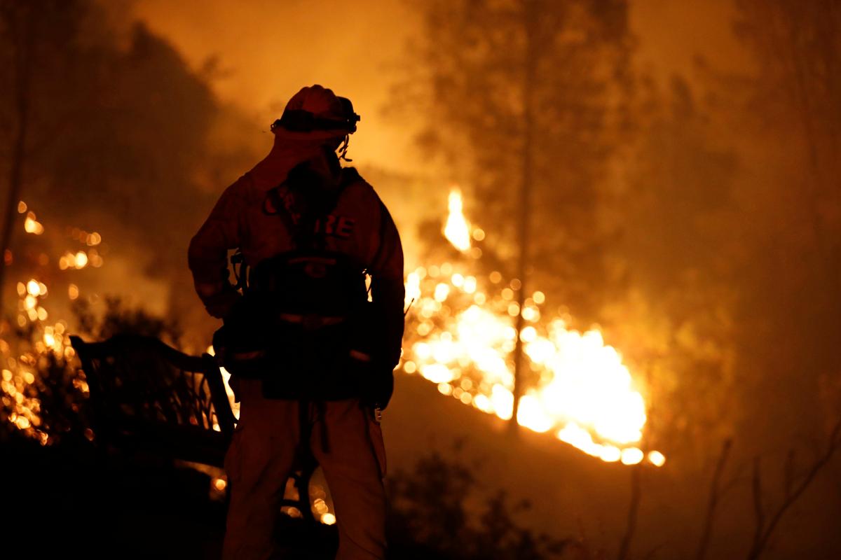 A firefighter watches flames advance up a hill towards homes as crews battle the Carr Fire, west of Redding, California, U.S. July 27, 2018. (REUTERS/Fred Greaves)