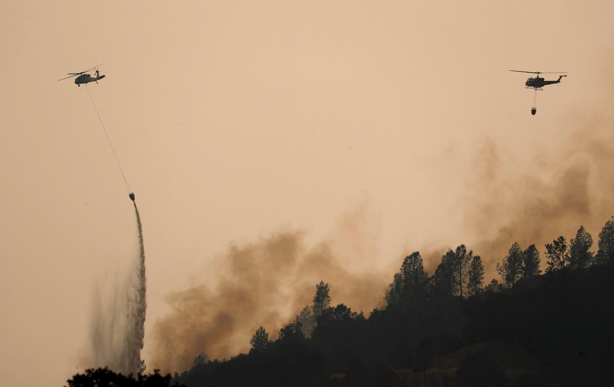 Helicopters drop water on hotspots of the Carr Fire burning in the hills west of Redding, California, U.S. July 27, 2018. (REUTERS/Fred Greaves)