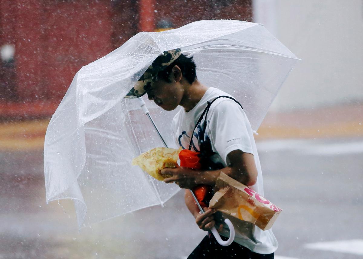 A passerby using an umbrella struggles against a heavy rain and wind as Typhoon Jongdari approaches Japan's mainland in Tokyo, Japan July 28, 2018. (REUTERS/Issei Kato)