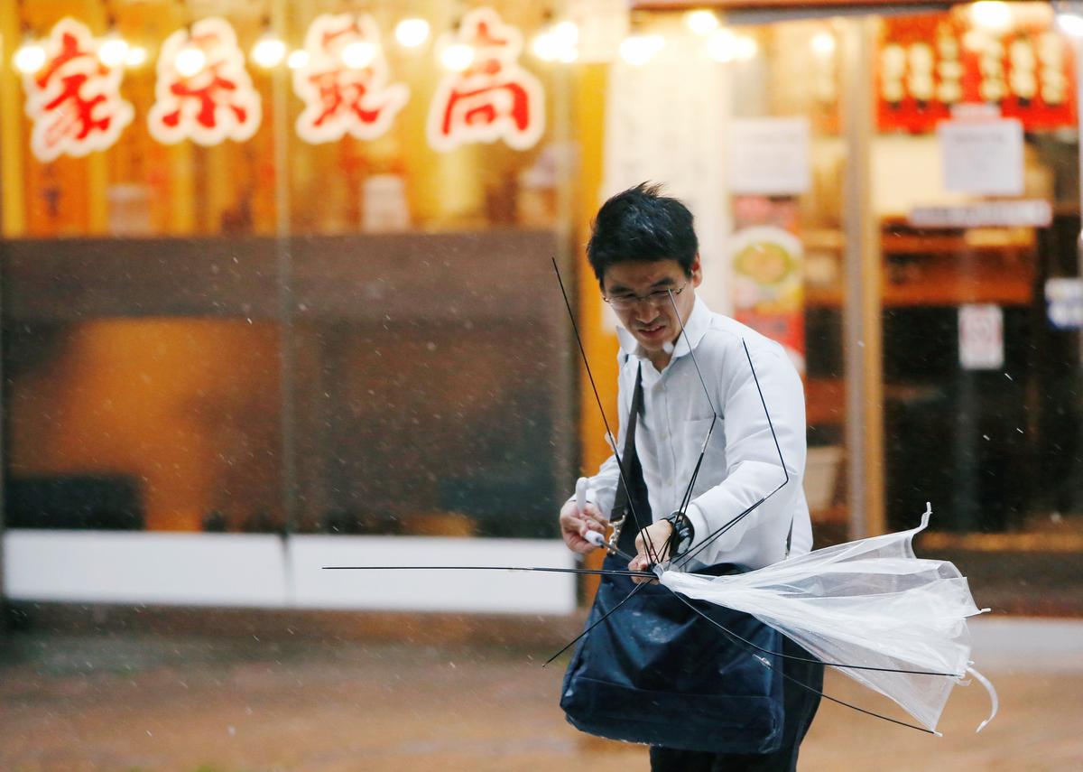 A man using an umbrella struggles against a heavy rain and wind as Typhoon Jongdari approaches Japan's mainland in Tokyo, Japan July 28, 2018. (REUTERS/Issei Kato)