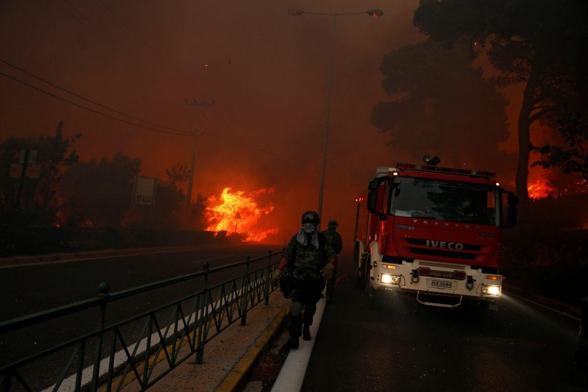 Soldiers fall back as a wildfire burns in the town of Rafina, near Athens, Greece on July 23, 2018. (REUTERS/Costas Baltas)