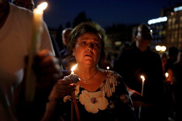 A woman holds a candle outside the parliament building to commemorate the victims of a wildfire that left at least 91 dead, in Athens, Greece, July 30, 2018. (Reuters/Costas Baltas)