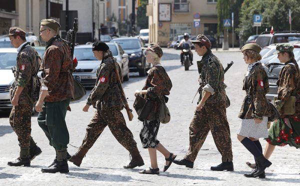 A group of scouts dressed and armed like the 1944 Warsaw Rising insurgents march with flowers in the Old Town district that saw severe fighting. (AP Photo/Czarek Sokolowski)