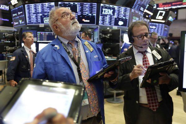 Traders Eugene Mauro, center, and Sal Suarino, right, work on the floor of the New York Stock Exchange on Aug. 2, 2018. (AP Photo/Richard Drew)