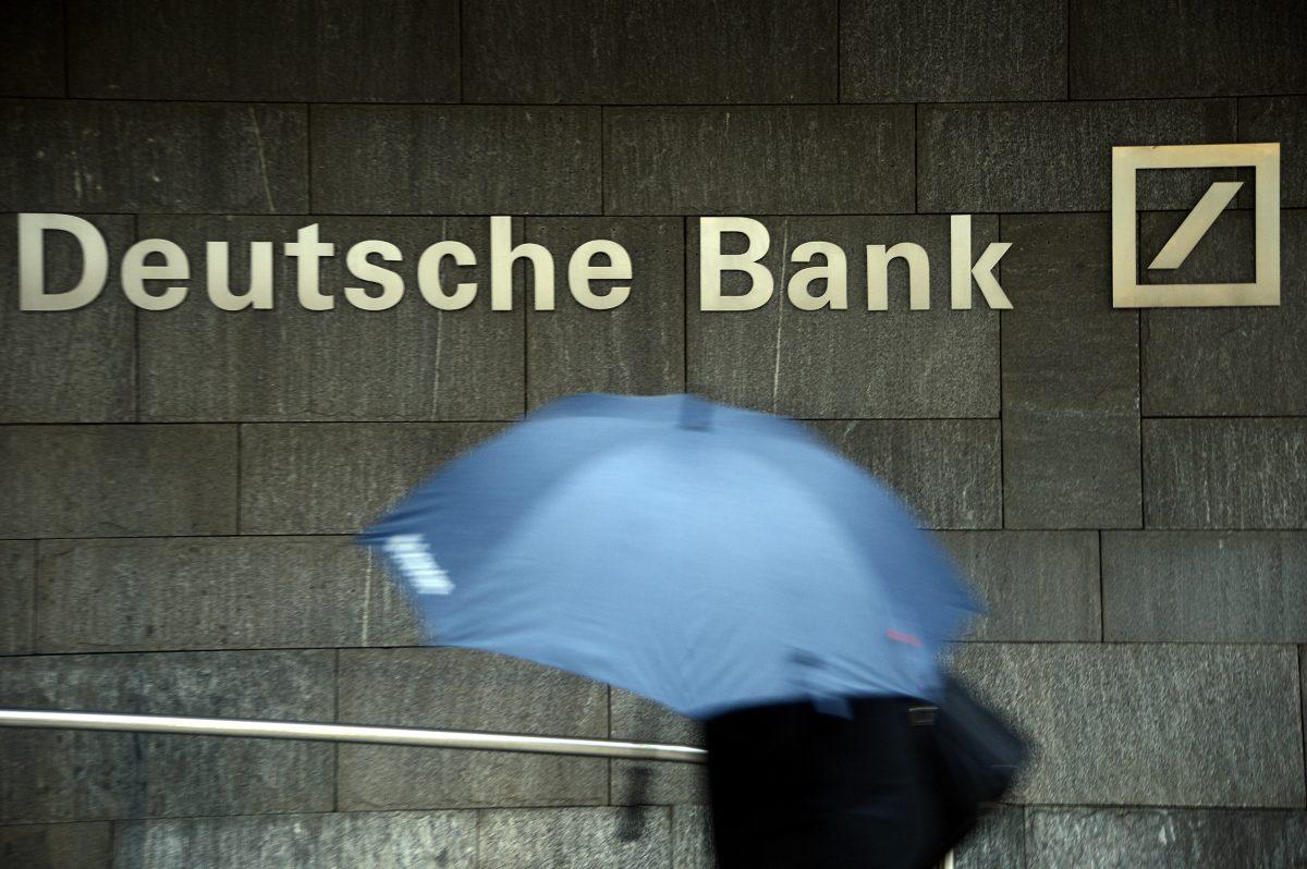 A woman with an umbrella passes a logo of Deutsche Bank in Frankfurt, Germany, on Jan. 29, 2013. (Thomas Lohnes/Getty Images)